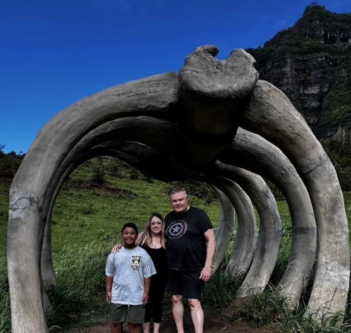 A group of people standing under a sculpture

Description automatically generated